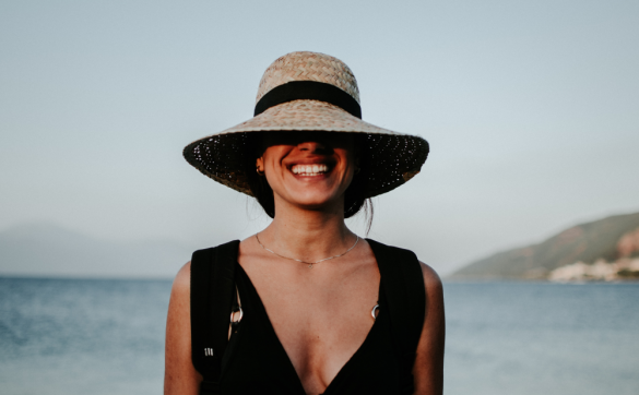 kobieta z uśmiechem w kapeluszu na tle morza