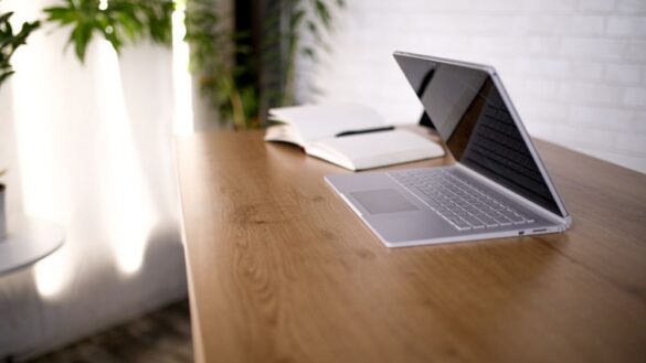 otwarty laptop i notatnik lezace na biurku